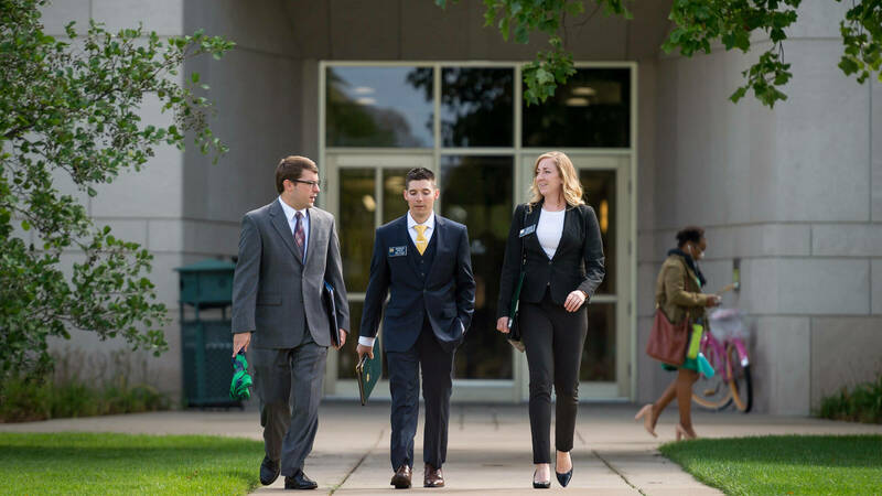 3 students walking out of Mendoza College of Business in formal business attire